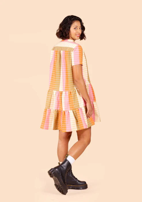 Woman wearing a colorful striped Poppy Dress on a beige background