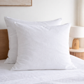 Two Pure white European linen pillowcases  on a bed in a bedroom setting.