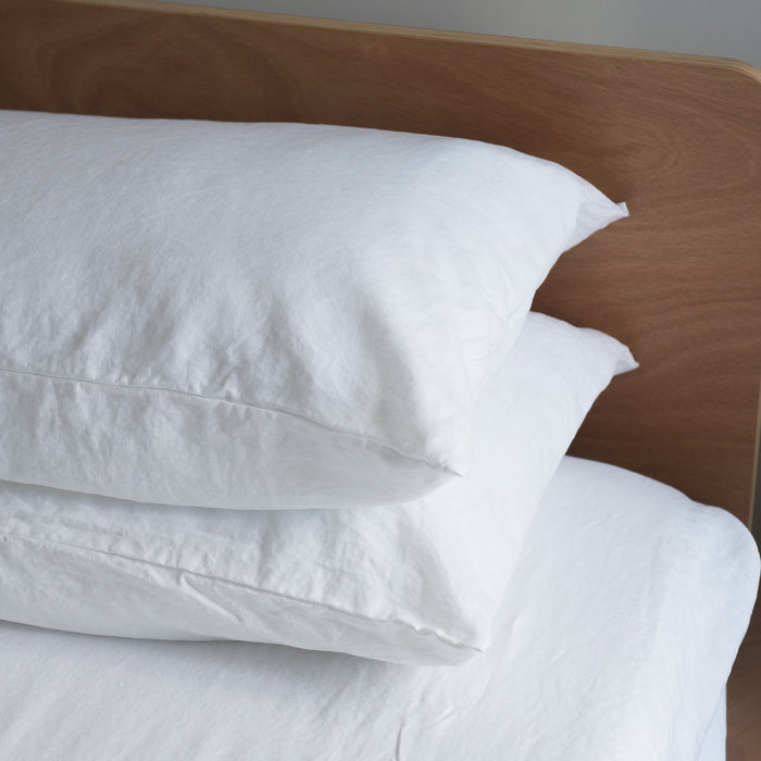 Pure white European linen pillowcases  on a wooden headboard