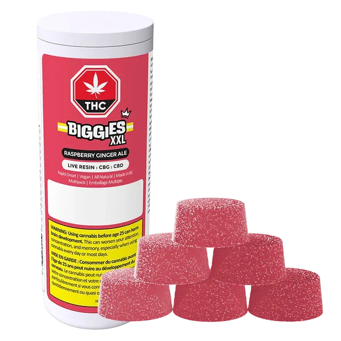 Angled view of a white canister labeled Biggies XXL with raspberry-red "Raspberry Ginger Ale Live Resin Gummies" branding beside a pyramid of six sugar-coated pink gumdrop-style gummies.