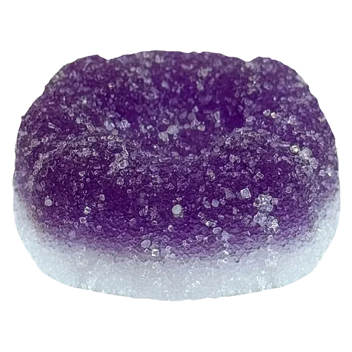 Close-up top view of a sugar-coated purple and white gummy, labeled Ratio'd Moon Berry THC:CBD:CBN Gummies, showing crystalline sugar texture and rounded dome shape.