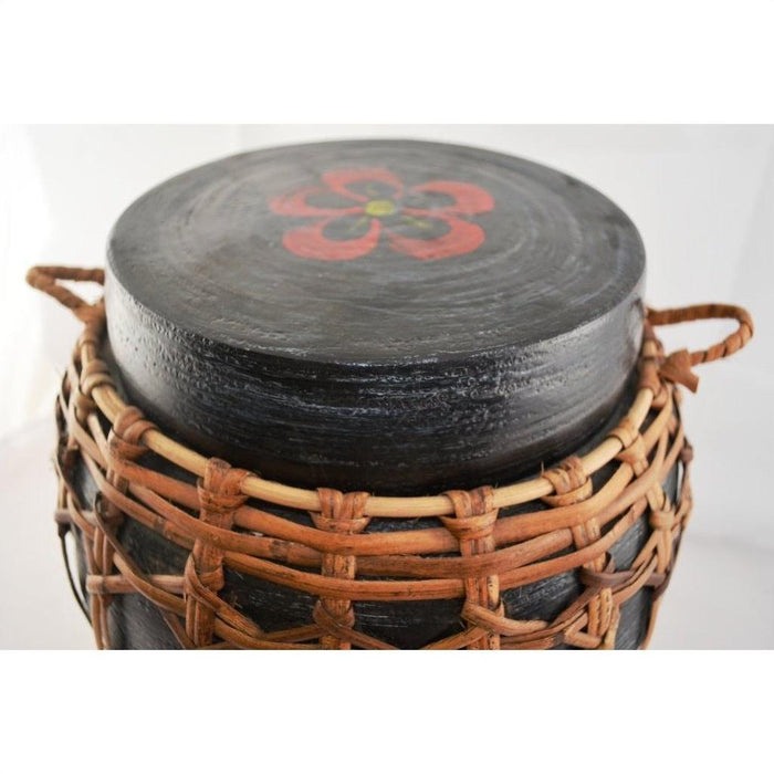 Black rattan and bamboo lidded basket with woven sides, handles, and red floral lid design, close-up view.
