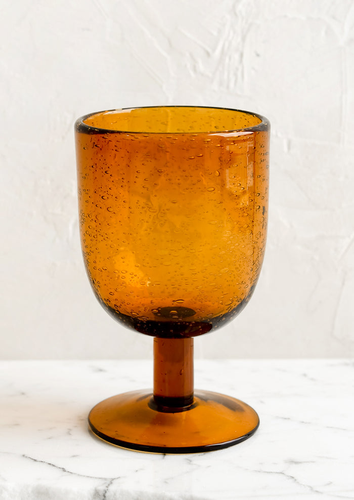 A short stemware glass in amber color.