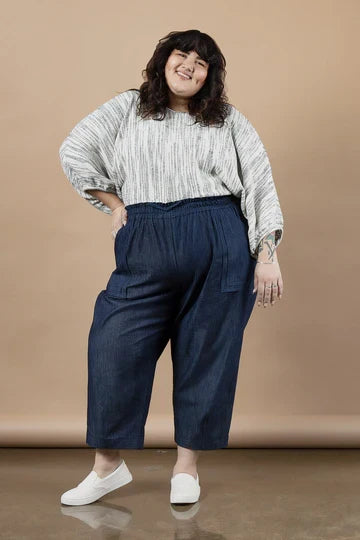 Woman wearing a white patterned top and blue pants made using Sepia Pants and Shorts sewing pattern  against a beige background