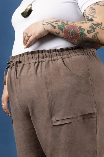 Brown pants made using Sepia Pants and Shorts sewing pattern  worn by a person with tattoos on a blue background
