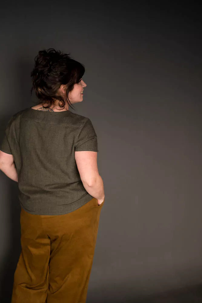 Person wearing a green shirt and brown pants against a dark background The 101 Trouser Sewing Pattern by Merchant & Mills – relaxed drawstring linen trousers for beginners
