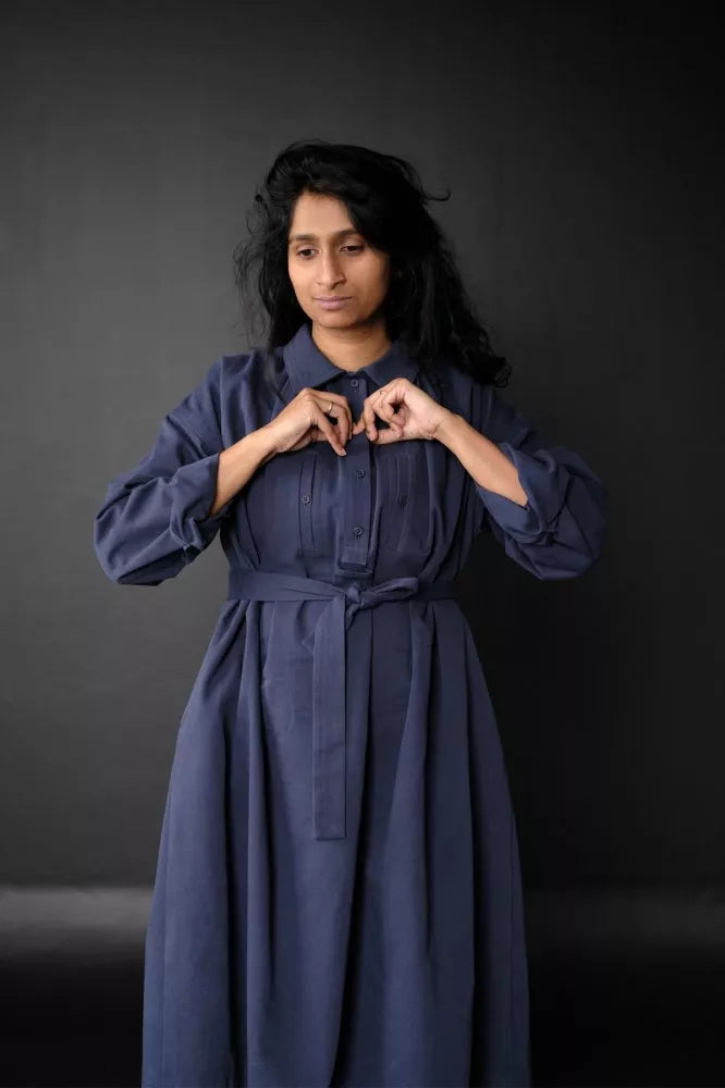 Woman wearing a long blue The Cawley Sewing Pattern by Merchant & Mills against a dark background