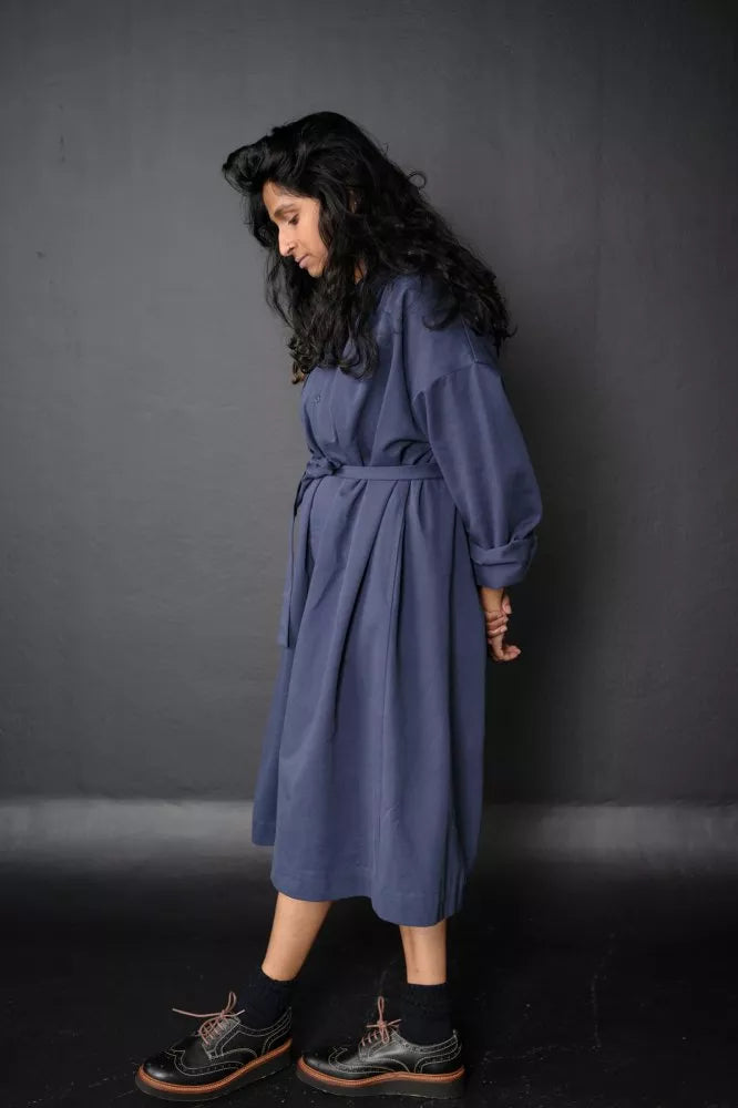 Woman wearing a blue The Cawley Sewing Pattern by Merchant & Mills against a dark gray background