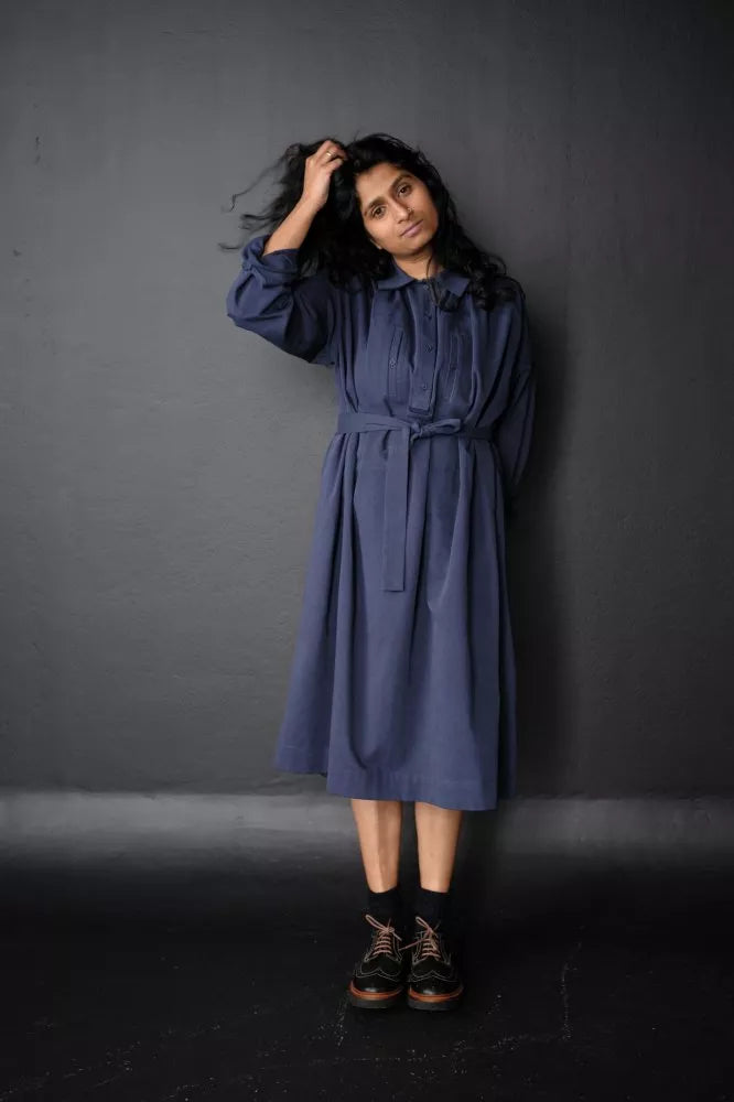 Woman wearing a blue The Cawley Sewing Pattern by Merchant & Mills  against a dark gray background