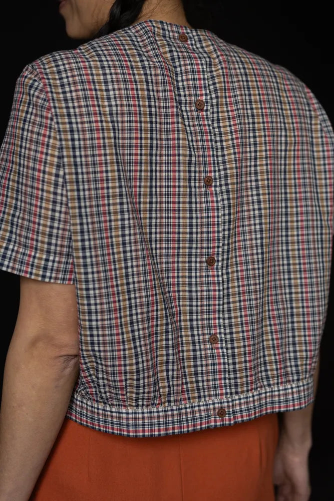 Person wearing a plaid top made using The Celeste Sewing Pattern by Merchant & Mills top made using The Celeste Sewing Pattern by Merchant & Millswith a black background