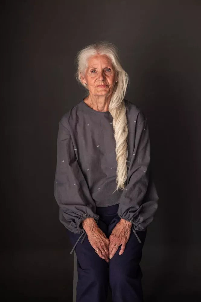 Woman with long white hair sitting against a black background