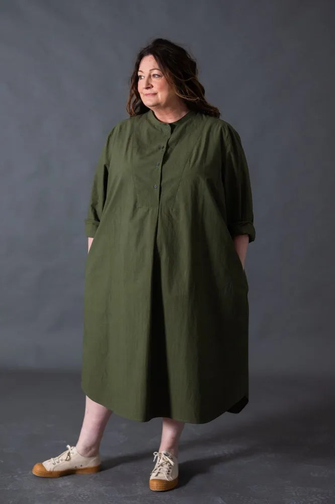 Woman wearing a green dress made using The Niven Sewing Pattern by Merchant & Mills  against a gray background