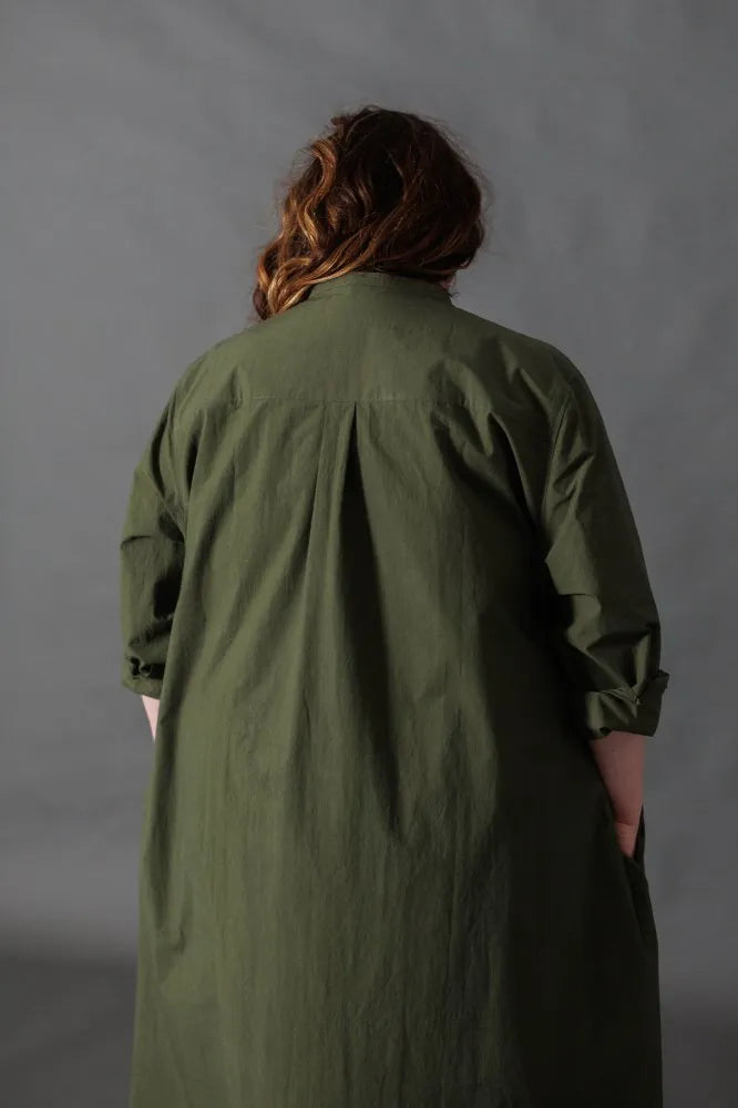Person wearing a green dress made using The Niven Sewing Pattern by Merchant & Mills against a gray background