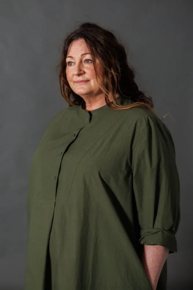 Woman wearing a green dress made using The Niven Sewing Pattern by Merchant & Mills  against a grey background
