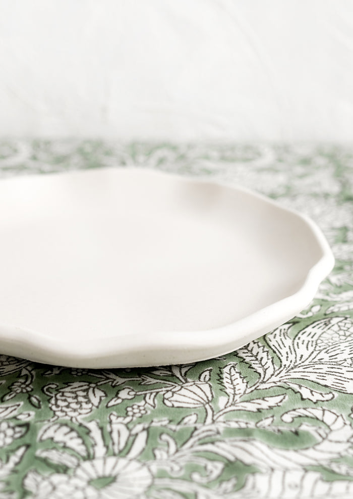 A round white concrete tray with ruffled, wavy edges.