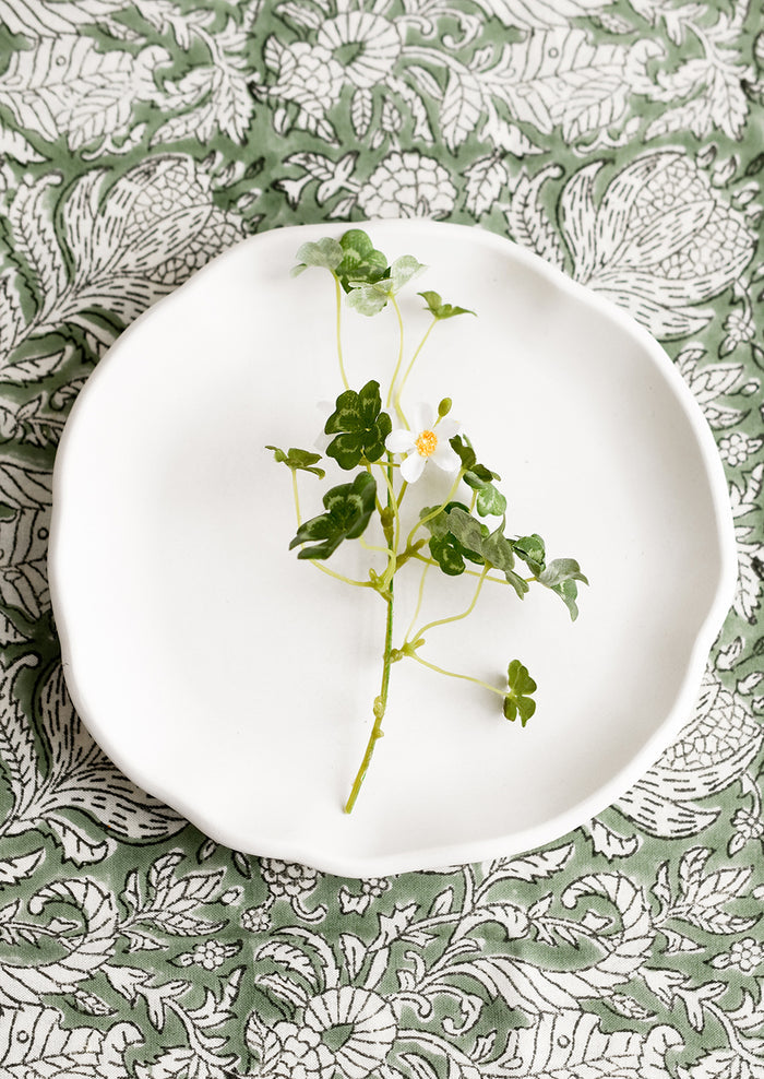 A round white concrete tray with ruffled, wavy edges.